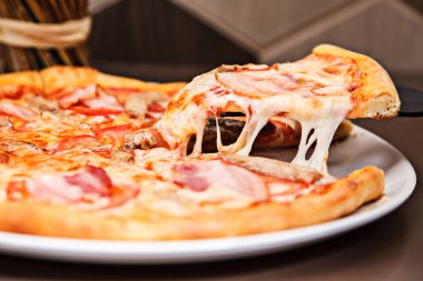 Bir lezzetli pizza dilim üzerinden düşen lezzetli peynir ile