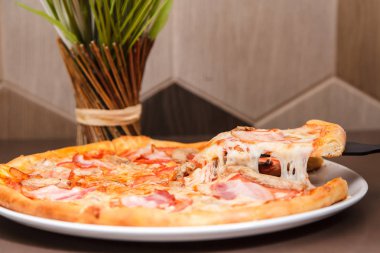 Bir lezzetli pizza dilim üzerinden düşen lezzetli peynir ile