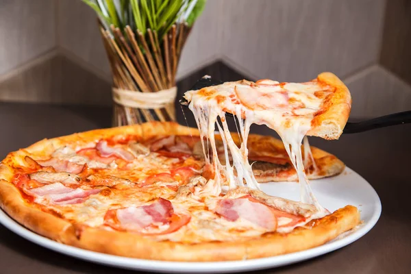 Bir lezzetli pizza dilim üzerinden düşen lezzetli peynir ile