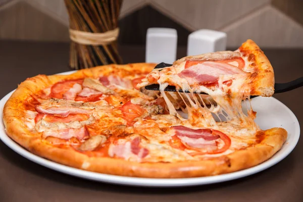 Bir lezzetli pizza dilim üzerinden düşen lezzetli peynir ile