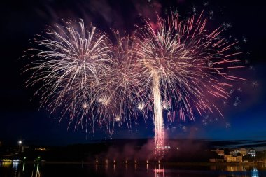 Su üzerinde gece gökyüzünde güzel piroteknik havai fişek gösterisi. Kutlama.