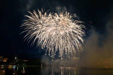 Su üzerinde gece gökyüzünde güzel piroteknik havai fişek gösterisi. Kutlama.