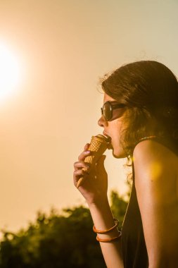 Genç kadın dondurma yeşil günbatımı sırasında yeme.
