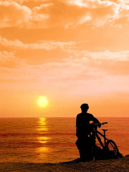 Boy with his bicycle resting and looking at the sea. Silhouette boy with his bicycle during sunset. Man with his bicycle outdoors by the sea against sunset. Summer.