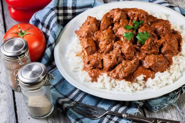 Chicken tikka masala served with rice in a white plate clipart