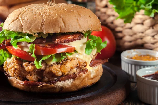 Delicious burger with chicken, bacon, tomato, cheese and lettuce served with french fries