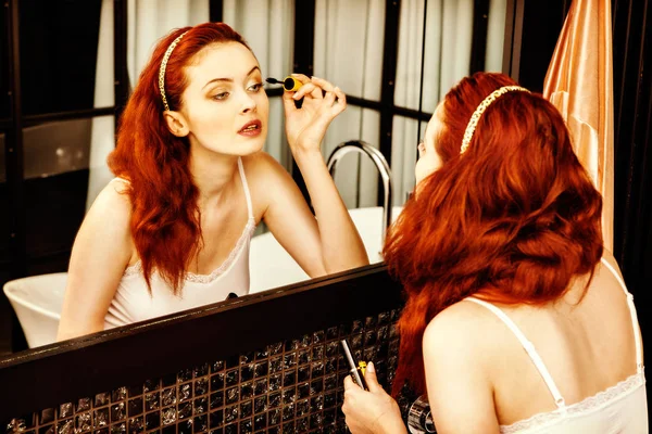 红头发的女人涂睫毛膏在家里的镜子的特写 — 图库照片
