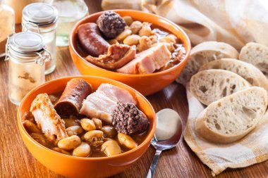 Bowl with fabada asturiana. Traditional spanish bean stew with chorizo, bacon and other meats clipart