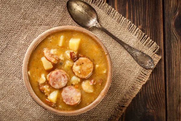 Wooden bowl of split pea soup with sausage, bacon and potatoes. Top view — Stock Image Wooden Bowl Split Pea Soup Sausage Bacon Potatoes Top View Stock Photo