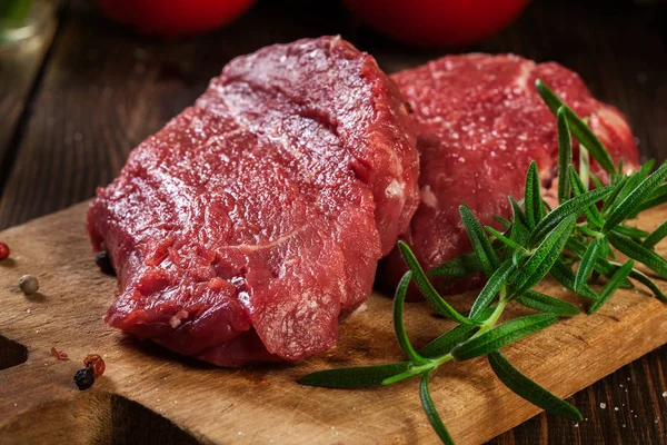 Fresh raw beef steak sirloin with rosemary on cutting board