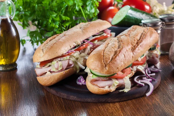Submarine sandwiches with ham, cheese and vegetables — Stock Photo, Image