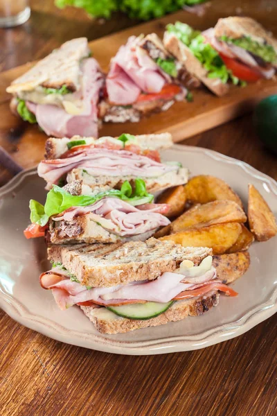 Сэндвичи с ветчиной, сыром, помидорами, салатом и огурцом — стоковое фото