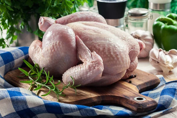 Frango cru inteiro na placa de corte de madeira — Fotografia de Stock