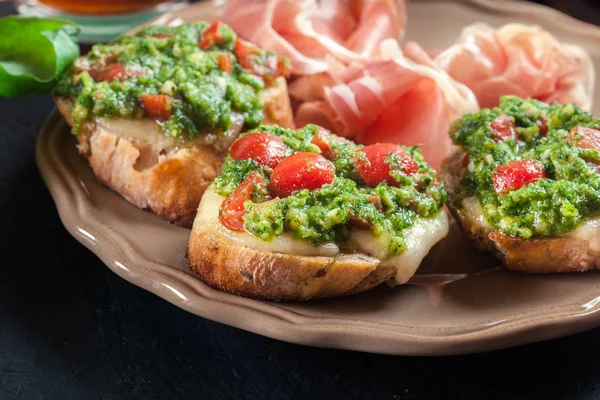 Bruschetta con pesto fresco, mozzarella y tomates cherry en un — Foto de Stock