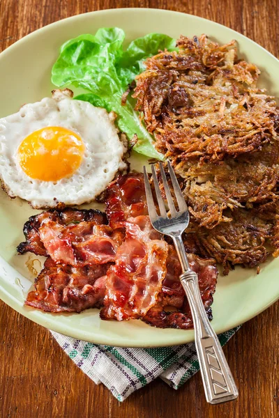 Hash browns. Aardappelpannenkoekjes met krokant gebakken bacon en gebakken ei — Stockfoto