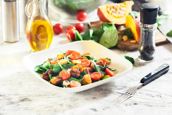 Roasted pumpkin salad with spinach, tomatoes and nuts — Stock Photo, Image