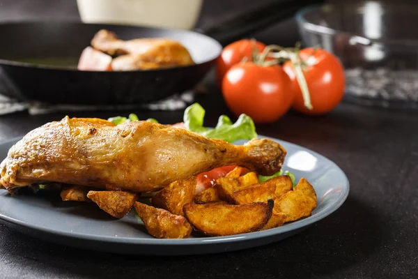 Gebraden kip benen met aardappel partjes en tomaten — Stockfoto