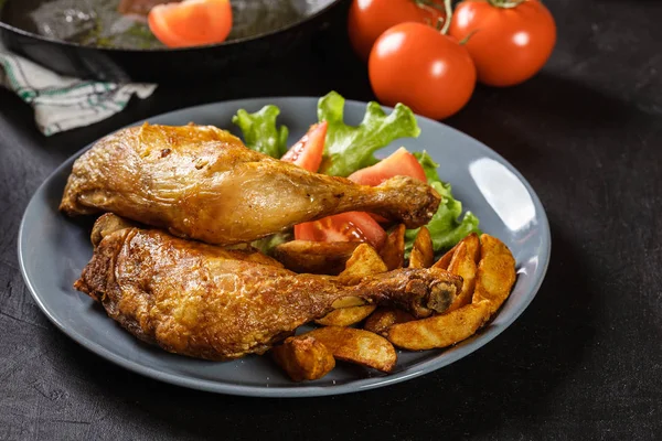 Gebraden kip benen met aardappel partjes en tomaten — Stockfoto