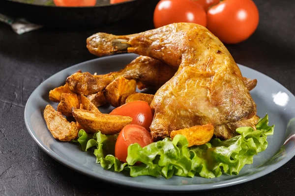 Roasted chicken legs with potato wedges and tomatoes — Stock Photo, Image