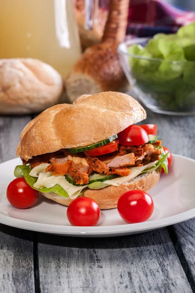 Fried chicken meat with cheese and vegetables in bun — Stock Photo, Image