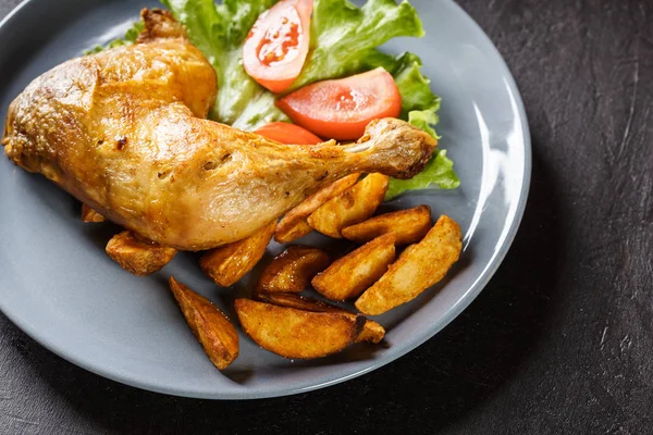 Gebraden kip benen met aardappel partjes en tomaten — Stockfoto