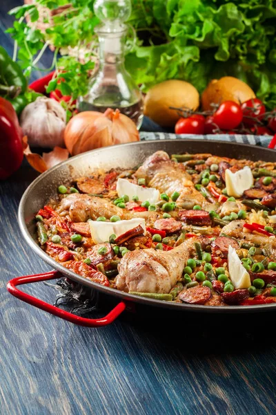 Paella tradizionale con cosce di pollo, chorizo di salsiccia e verdure servite in paellera — Foto Stock