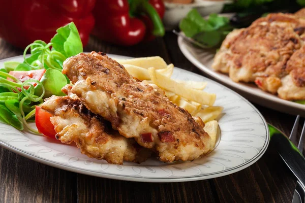 Chicken medallions with red peppers served with chips — Stock Photo, Image