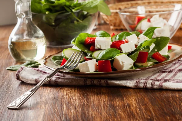 Ensalada de espinacas frescas con feta, pepino y pimentón rojo en un plato . —  Fotos de Stock