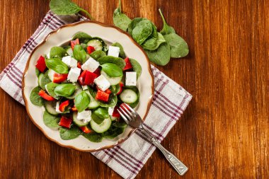 Fresh spinach salad with feta, cucumber and red paprika on a pla clipart