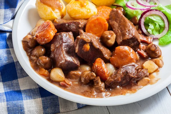 Ragoût de boeuf bourguignon servi avec des pommes de terre au four — Photo