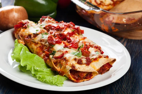 Traditional mexican enchiladas with chicken meat, spicy tomato sauce and cheese on a plate — Stock Image Traditional mexican enchiladas with chicken meat, spicy tomato sauce and cheese on a plate Royalty Free Stock Photos