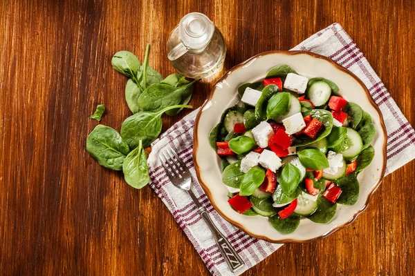 Ensalada de espinacas frescas con feta, pepino y pimentón rojo en un pla —  Fotos de Stock