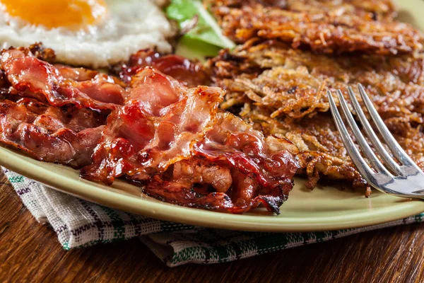 Hash browns. Aardappelpannenkoekjes met krokant gebakken bacon en gebakken ei — Stockfoto