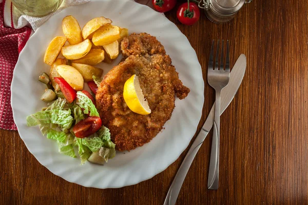 Breaded viennese schnitzel with baked potatoes — Stock Photo, Image