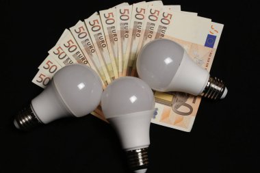 Para ile siyah arka plan üzerinde ampul tasarruflu.