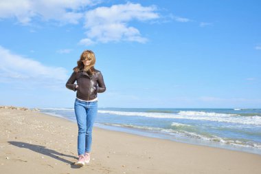 Sahilde yürüyüş ve plaj havası gidiyor rahat orta yaşlı kadın tam uzunlukta. 