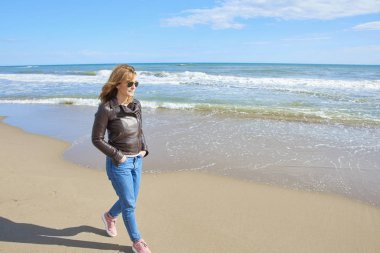 Sahilde yürüyüş ve plaj havası gidiyor rahat orta yaşlı kadın tam uzunlukta. 