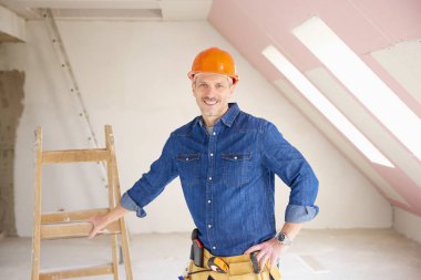 Kendine güvenen orta yaşlı tamirci inşaat alanında ayakta. 