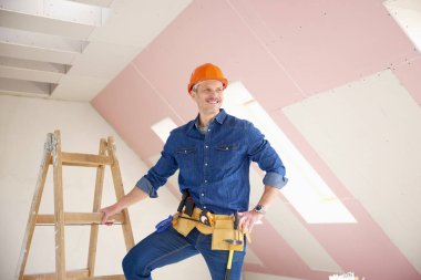 Kendine güvenen orta yaşlı tamirci inşaat alanında ayakta. 