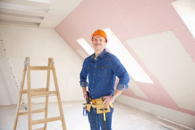 Kendine güvenen orta yaşlı tamirci inşaat alanında ayakta. 