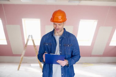 Pano elinde tutan ve inşaat sahasında dururken bir şey yazma el ulağı orta yaşlı.