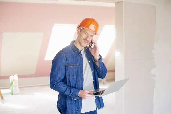 Sonriente Hombre Construcción Haciendo Llamada Uso Ordenador Portátil Mientras Que —  Fotos de Stock