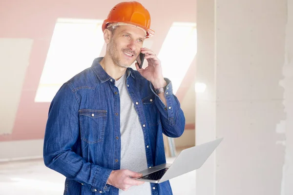 Constructie Man Maken Oproep Met Behulp Van Zijn Laptop Terwijl — Stockfoto