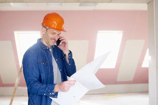 Mellersta Byggnadsarbetare Som Håller Planen Handen Medan Använder Mobiltelefon Och — Stockfoto