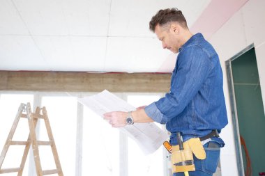 Blueprint duran inşaat sahasında izlerken mühendisi orta yaşlı. 