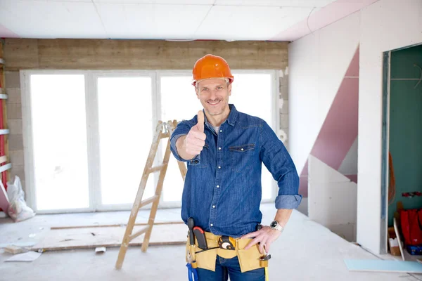Portrait of smiling handyman wearing safety helmet and showing thumb up while looking at camera and smiling.