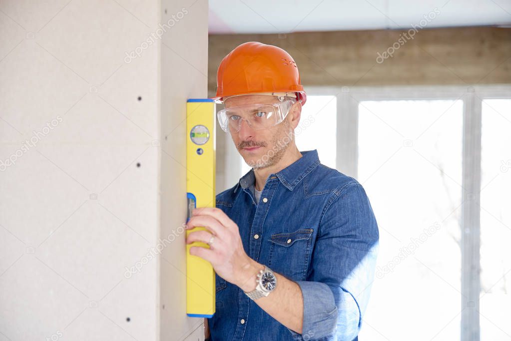 Clsoe-up of handyman using spirit level while working on construction site.