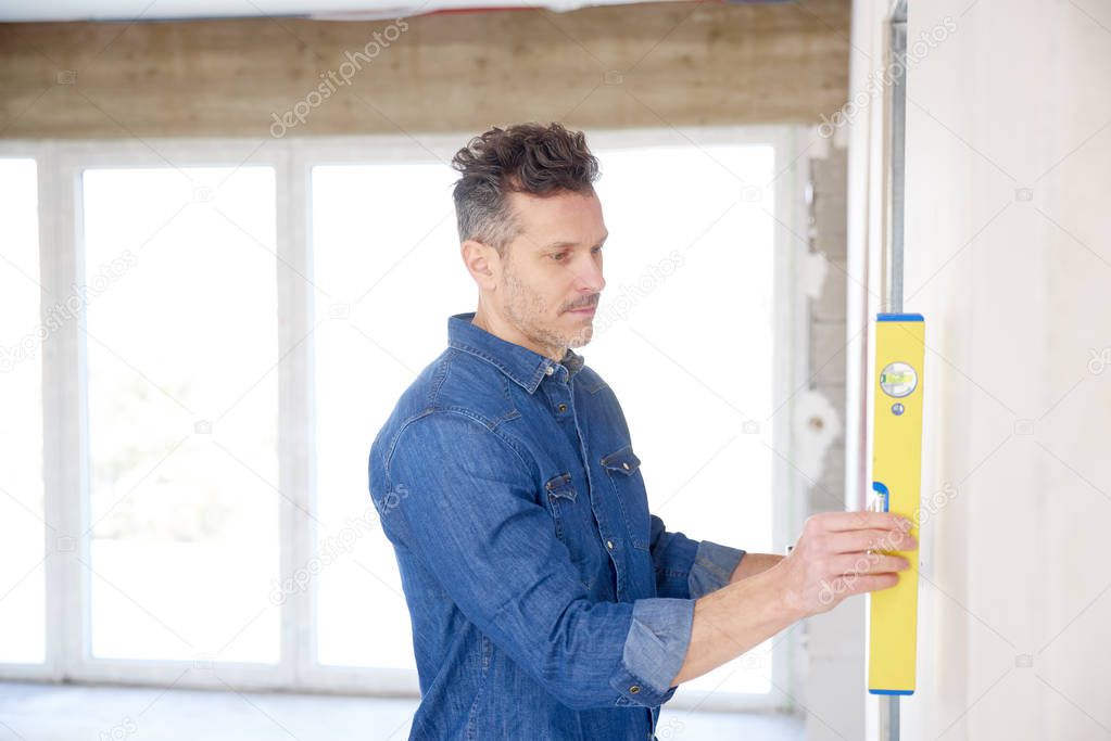 Handyman using spirit level while working on construction site. 