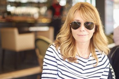 Orta gülümseyen, yakın çekim portre bistro oturan ve rahatlatıcı bir kadın yaşlı. 