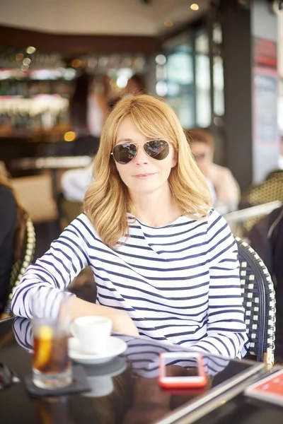 Açık bir kafede kahve yaparken rahatlatıcı kendinden emin ve gülümseyen Olgun kadın portresi.